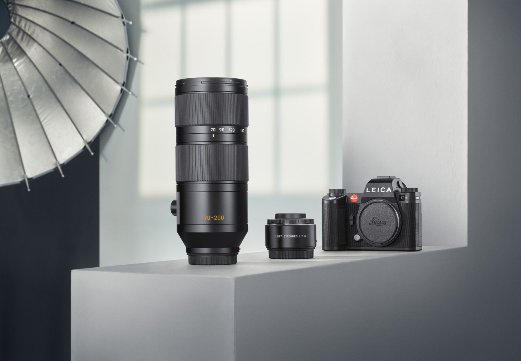 Two Leica photo lenses and a digital leica camera body stand on a still life photo set